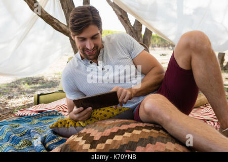 Relaxed young man using digital tablet in tent Stock Photo