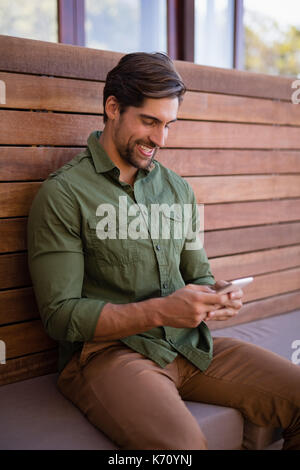 Happy man using mobile phone in cottage Stock Photo