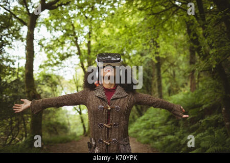 Woman with arms outstretched wearing virtual reality simulator at forest Stock Photo