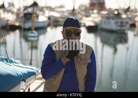 Yachtsman using walkie talkie on pier Stock Photo