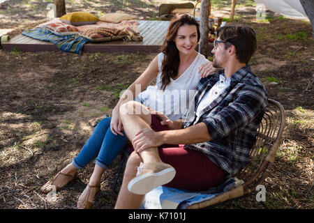 Full length of young couple relaxing on chairs at field Stock Photo