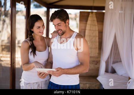 Happy couple using digital tablet in cottage during safari vacation Stock Photo