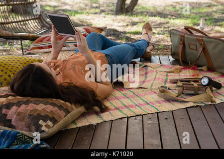 Woman using digital tablet while lying down in tent Stock Photo