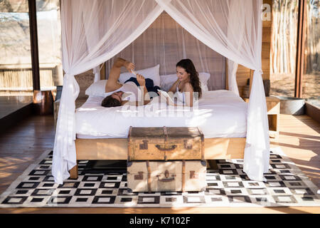 Smiling couple using digital tablet on bed in cottage Stock Photo
