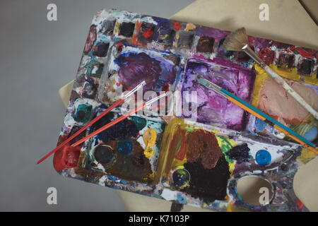 Paintbrushes on palette in art studio Stock Photo