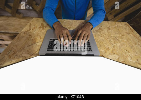 Midsection of young man using laptop at table in cafeteria Stock Photo