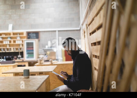 Side view of young man using digital tablet while sitting in cafe Stock Photo