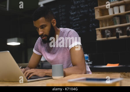 Young man using laptop computer while sitting at table in cafe Stock Photo