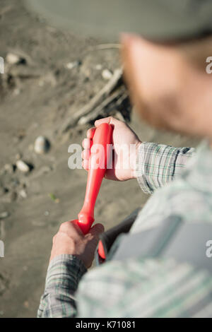 High angle view of man holding fishing tool while standing at riverbank Stock Photo