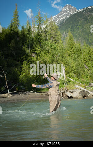 Side view of man fishing in river against mountain Stock Photo