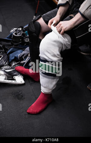 Low section of male ice hockey player wearing sock in dressing room Stock Photo