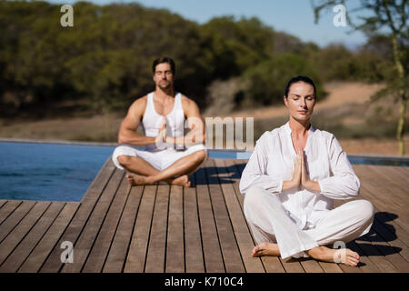 Couple performing yoga at safari vacation on a sunny day Stock Photo