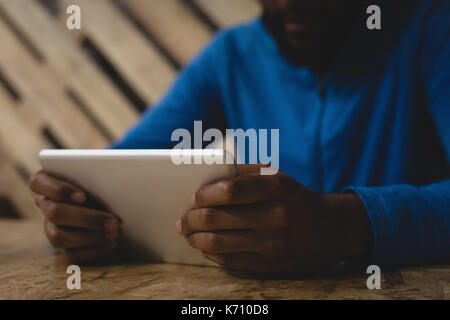 Midsection of man using digital tablet while sitting at table in cafe Stock Photo