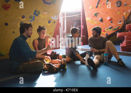 Friends having food and drink while sitting in gym Stock Photo