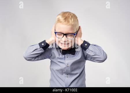 Isolated portrait of gaucasian boy covering ears with hands. Stock Photo