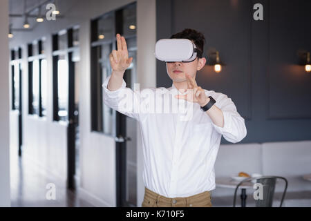 Businessman wearing virtual reality simulator in corridor at office Stock Photo