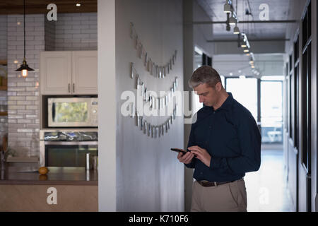 Businessman using mobile phone in corridor at office Stock Photo