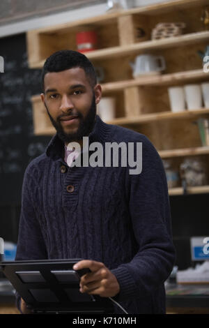 Portrait of owner using computer while standing at bar counter in cafe Stock Photo