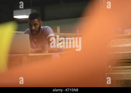 Young man using laptop while sitting in cafeteria Stock Photo