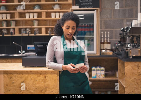 Beautiful waitress using mobile phone at counter in cafÃƒÂ© Stock Photo