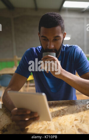 Young man having coffee while using tablet computer at table in cafe Stock Photo
