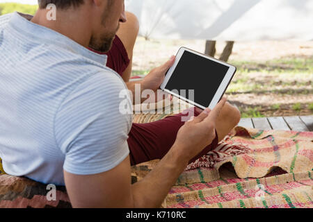 Relaxed young man using digital tablet in tent Stock Photo