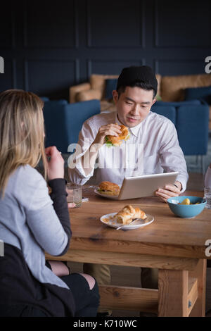 Businessman with colleague using digital tablet at table in office cafeteria Stock Photo