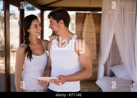 Happy couple using digital tablet in cottage during safari vacation Stock Photo