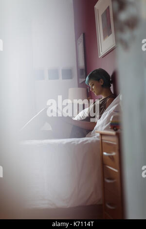 Relaxed young woman using phone on bed at home Stock Photo