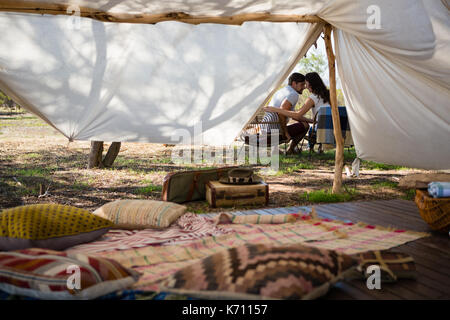 Romantic young couple sitting on chairs outside tent Stock Photo