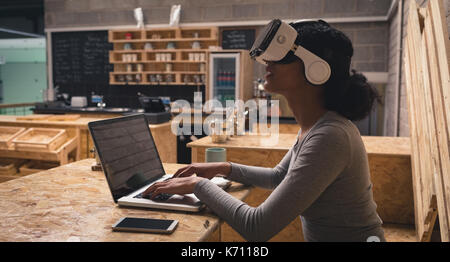 Woman using virtual reality headset while working on laptop in cafÃƒÂ© Stock Photo