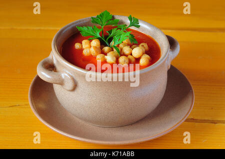 Tomato soup with croutons and parsley in a clay bowl on a wooden table. Stock Photo