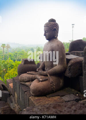 JOGJA, INDONESIA - AUGUST 12, 2O17: Close up of buddha statue and stupa at Borobudur Buddhist temple Candi Borobudur . Built in 9th century, cataloged as UNESCO World Heritage Site. Central Java, Indonesia Stock Photo