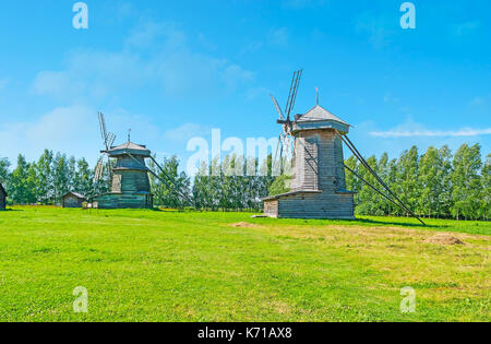 The beauty of Russian nature and historic objects - the log windmills on the meadow in Wooden Architecture museum in Suzdal, Russia. Stock Photo
