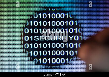 Binary code, Password security, hand holding magnifying glass showing exploit Stock Photo