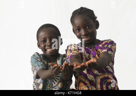 Two African children showing their palms asking begging for something, whilst smiling, isolated on white Stock Photo