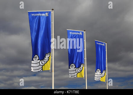 Company flags with logo Bibendum figure flying dark cloud sky, Michelin factory and research establishment, Almeria, Spain Stock Photo