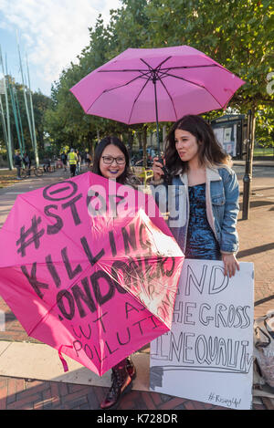 London, UK. 14th September 2017. Campaigners from 'Stop Killing Londoners' hold pink umbrellas at Windrush Square before walking to the crossing at Brixton Underground station. They then walked onto the pedestrian crossing and stopped traffic in a protest against London's excessive air pollution, due mainly to traffic. The air on the Brixton Road breaches the annual pollution limit in only 5 days, roughly 70 times the limit per year. Toxic air pollution results in 10,000 premature deaths in London each year and is particularly harmful to the elderly and the very young. To cut the disruption to Stock Photo