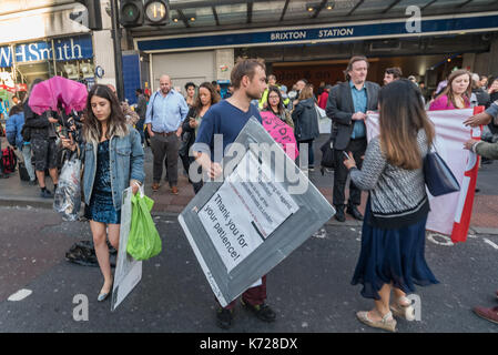 London, UK. 14th September 2017. Campaigners from 'Stop Killing Londoners' walk onto the crossing at Brixton Underground station to block the road in a protest against London's excessive air pollution, due mainly to traffic. The air on the Brixton Road breaches the annual pollution limit in only 5 days, roughly 70 times the limit per year. Toxic air pollution results in 10,000 premature deaths in London each year and is particularly harmful to the elderly and the very young. To cut the disruption to traffic they moved out of the road after around five minutes, allowed the traffic build up to m Stock Photo