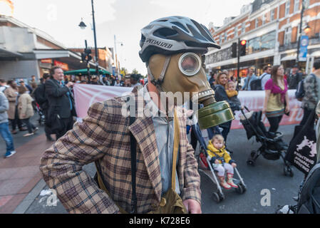 London, UK. 14th September 2017. Campaigners from 'Stop Killing Londoners', one in a gas mask, block the crossing at Brixton Underground station block the road in a protest against London's excessive air pollution, due mainly to traffic. The air on the Brixton Road breaches the annual pollution limit in only 5 days, roughly 70 times the limit per year. Toxic air pollution results in 10,000 premature deaths in London each year and is particularly harmful to the elderly and the very young. To cut the disruption to traffic they moved out of the road after around five minutes, allowed the traffic  Stock Photo