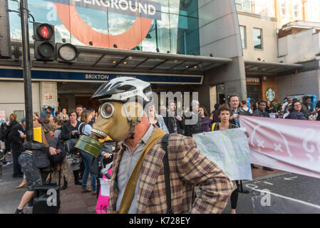 London, UK. 14th September 2017. A campaigner from 'Stop Killing Londoners' wears a gas mask on the crossing at Brixton Underground station as they block the road in a protest against London's excessive air pollution, due mainly to traffic. The air on the Brixton Road breaches the annual pollution limit in only 5 days, roughly 70 times the limit per year. Toxic air pollution results in 10,000 premature deaths in London each year and is particularly harmful to the elderly and the very young. To cut the disruption to traffic they moved out of the road after around five minutes, allowed the traff Stock Photo