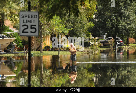 Altamonte Springs, United States. 14th Sep, 2017. September 14, 2017- Altamonte Springs, Florida, United States - A man carrying a dog is seen reflected in flood waters in the street in the Spring Oaks neighborhood of Altamonte Springs, Florida on September 14, 2017. Emergency workers used boats and trucks to rescue more than 50 residents on September 11, 2017 when water from the nearby Little Wekiva River swamped their homes in the wake of Hurricane Irma. Credit: Paul Hennessy/Alamy Live News Stock Photo