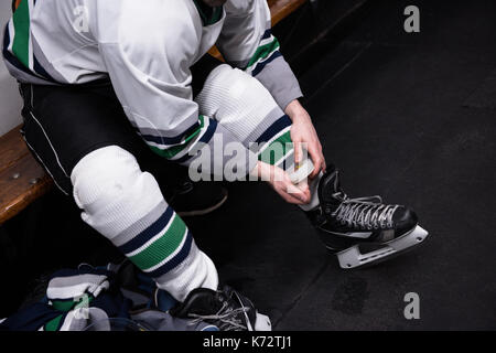 Low section of male ice hockey player wearing skate in dressing room Stock Photo
