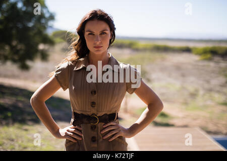 Portrait of woman standing with hand on hip during safari vacation Stock Photo