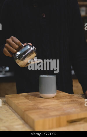 Midsection of owner making coffee while standing at bar counter in cafe Stock Photo