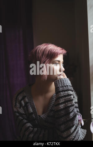 Thoughtful young woman looking away at home Stock Photo