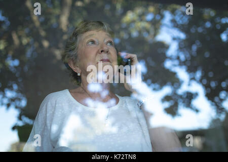 Senior woman talking on mobile phone at home Stock Photo