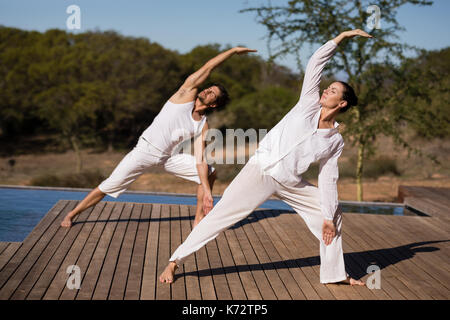 Couple performing yoga at safari vacation on a sunny day Stock Photo