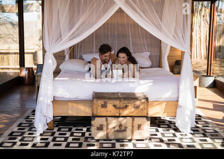 Smiling couple using digital tablet on bed in cottage Stock Photo