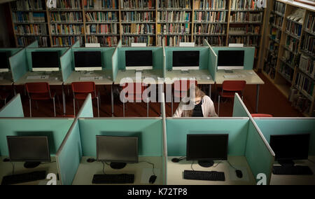 Woman sitting at desk in library room Stock Photo